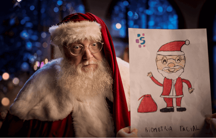 Papai noel segurando um desenho de papai noel feito por uma criança