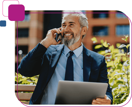 Homem de terno sentado falando ao celular com tablet na mão