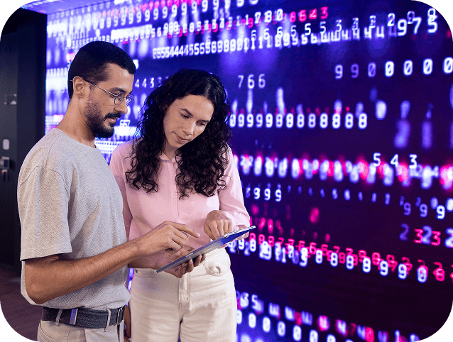 Homem e mulher analisando dados digitais em um ambiente de tecnologia.