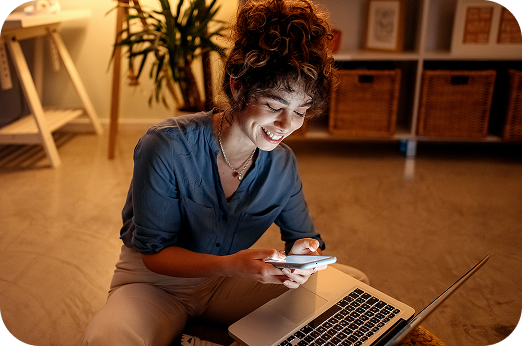 mulher mexendo no celular com um notebook no colo
