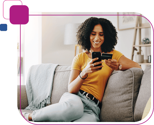 Mulher sentada, segurando o celular com uma mão e, na outra, um cartão de crédito, representando onde aplicar a solução Perfil Laranja.