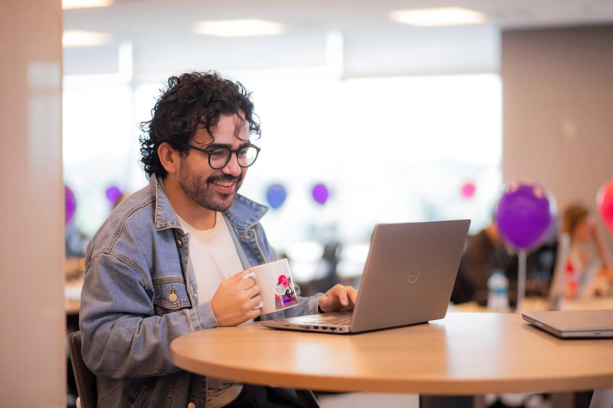 Homem segurando uma caneca enquanto usar o computador sorrindo