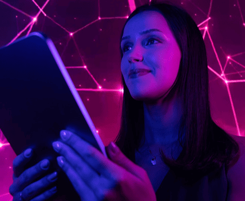 Mulher jovem usando celular em ambiente com iluminação neon roxa, simbolizando tecnologia e inovação, ideal para temas de networking e interatividade digital.