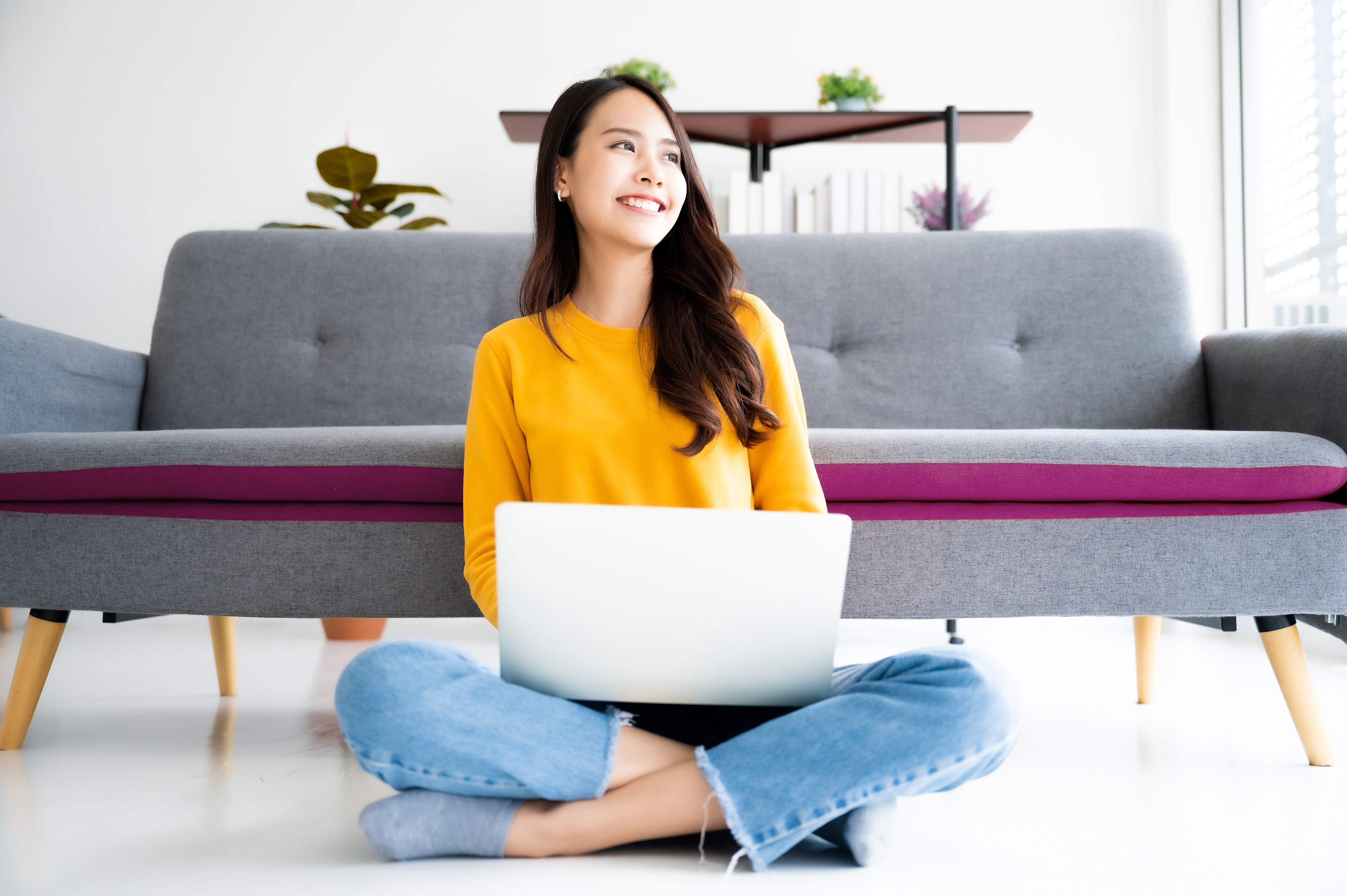 Beautiful young asian woman sitting on the floor working using computer laptop feeling happy relax and smile