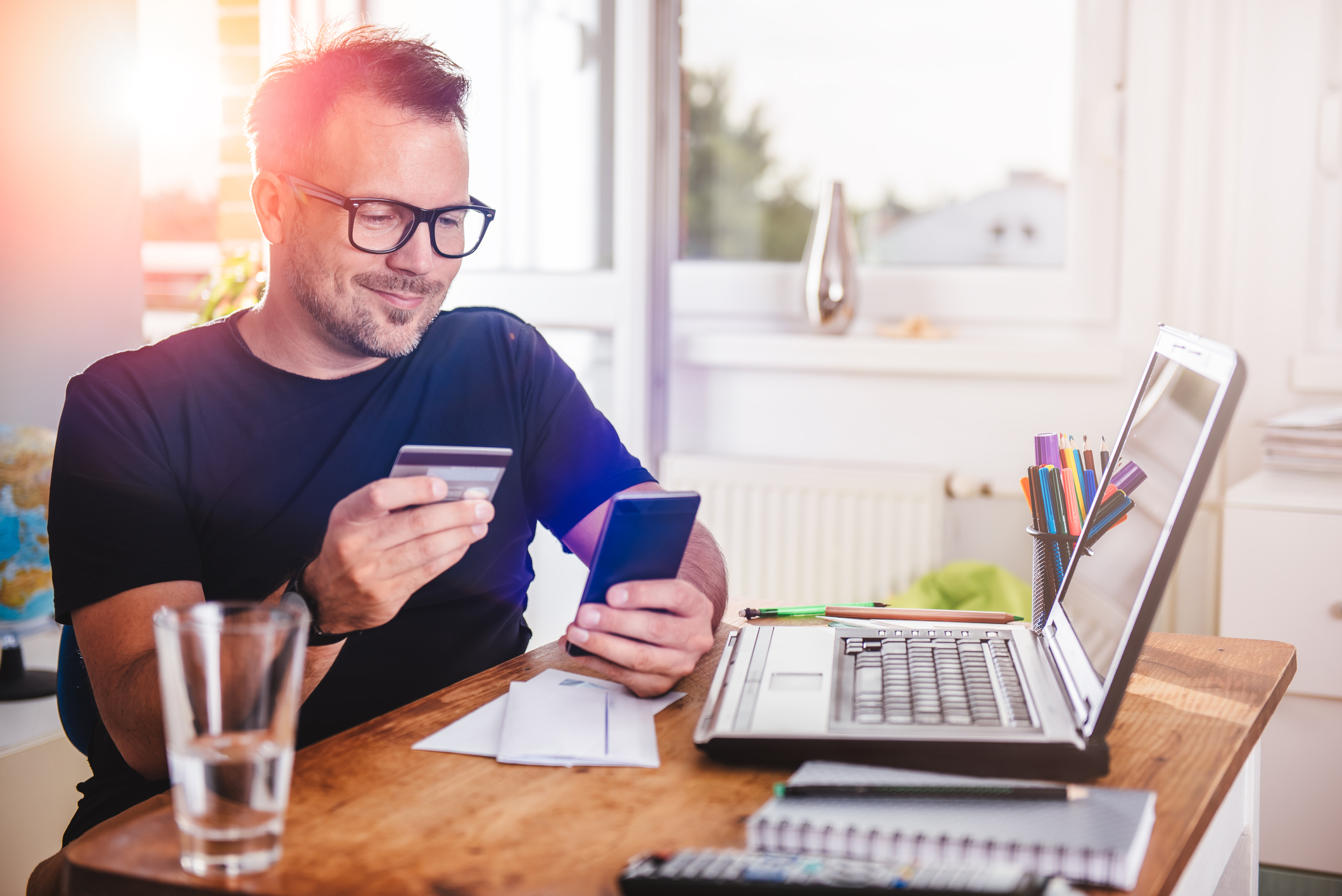 Man paying with credit card on smart phone at home office