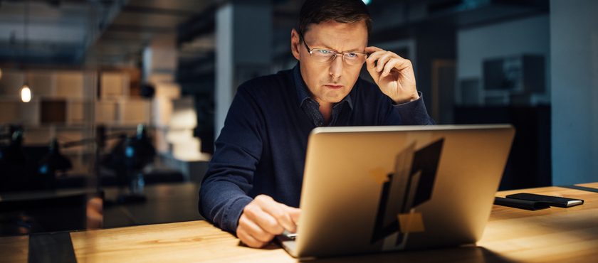 Confident businessman working late on laptop while sitting at desk in office