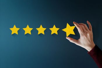Mão segurando estrelas, fazendo a avaliação de clientes - que significa a avaliação de clientes e de como fazer a formação de carteira