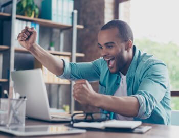 Empreendedor olhando o computador e comemorando o seu sucesso.