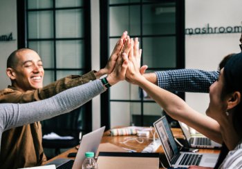 equipe de uma micro empresa motivada e comemorando suas conquistas todos de mãos juntas.