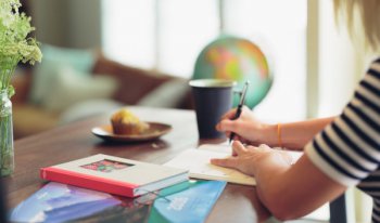 Empreendedora sentada estudando com livros em volta, reforçando o quão importante é investir tempo e dinheiro em capacitação.