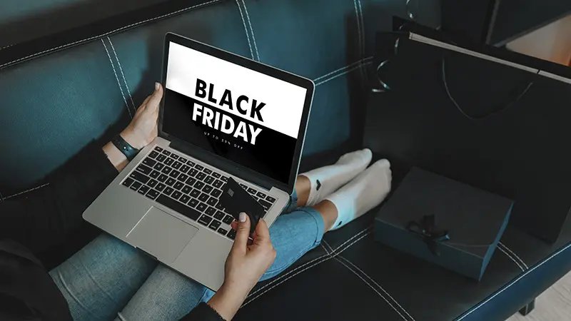 Jovem compra online na Black Friday em casa no notebook