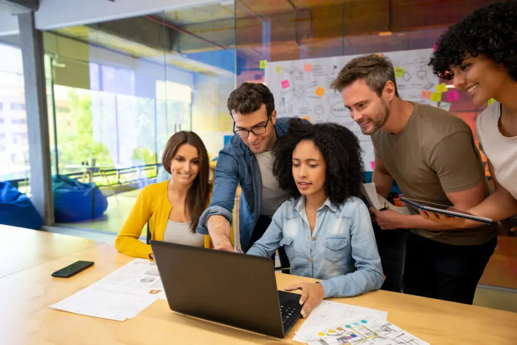 grupo de pessoas no ambiente corporativo olhando para o laptop e discutindo ideias