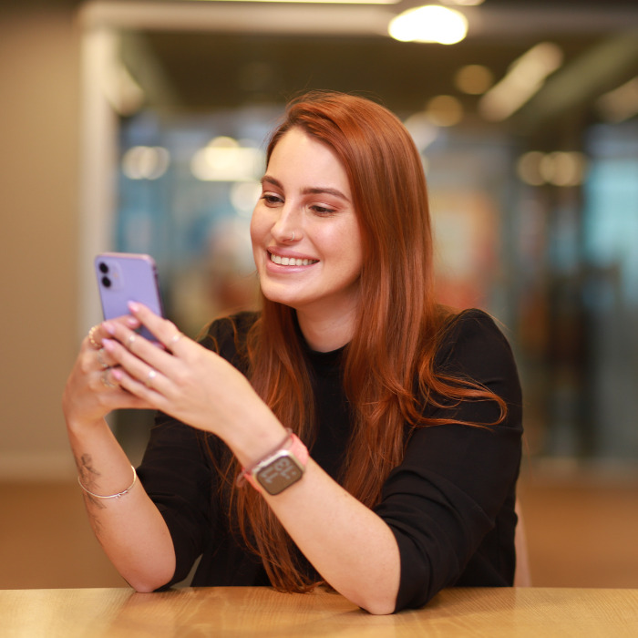 Mulher sorridente olhando para o celular