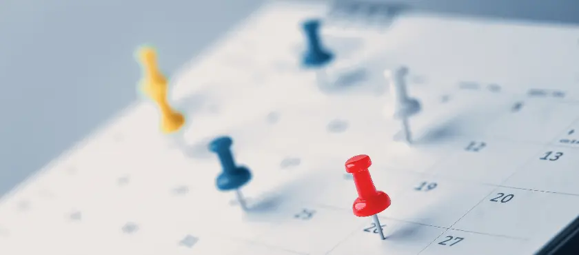 A imagem mostra uma folha de calendário com alguns pins, marcando datas importantes e feriados