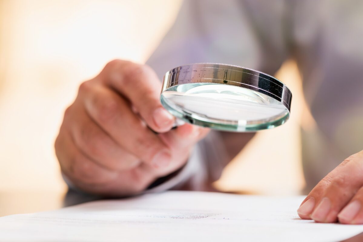 homem segurando lupa para investigar documento